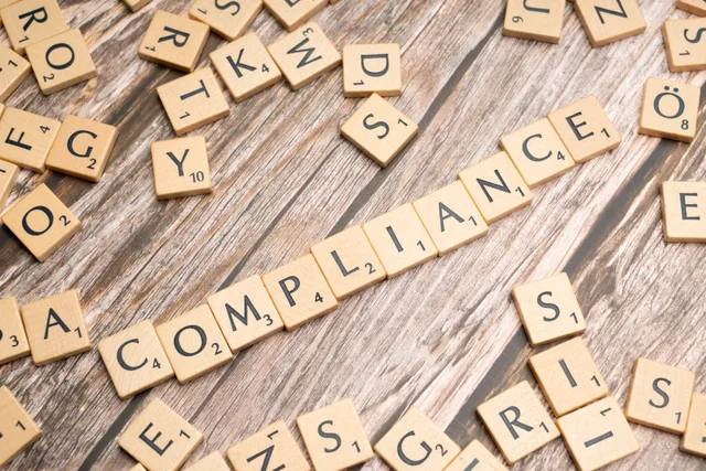 Wooden letter tiles forming the word 'COMPLIANCE' on a rustic wooden background. Common network marketing compliance questions answered