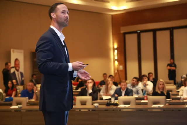 A dynamic speaker engages professionals during a business conference presentation. Training questions network marketing leaders ask, with a short guide