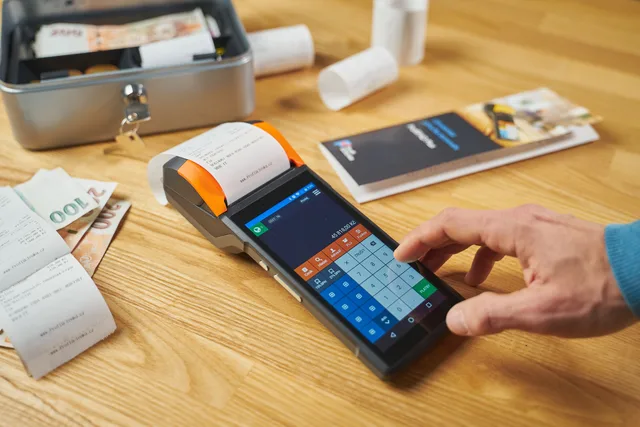 Person using a digital payment terminal on a wooden desk with cash and receipts visible. Direct selling benchmarks: the baseline numbers worth tracking