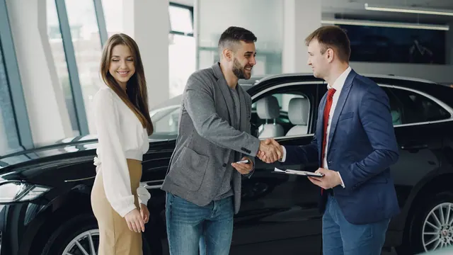 Buyers and sales representative shake hands at a car dealership for a successful car purchase. Distributor onboarding explained for business teams in 2027