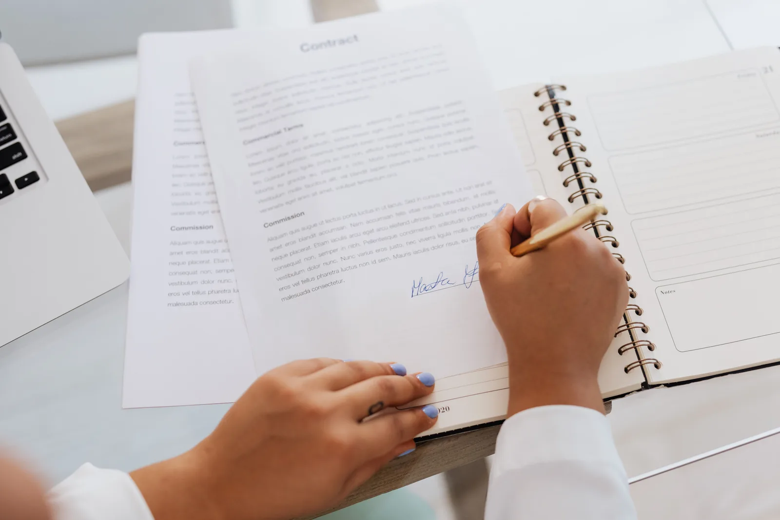 Close-up of hands signing a contract on a desk with office supplies, symbolizing legal agreements. Reading the distributor onboarding examples closely