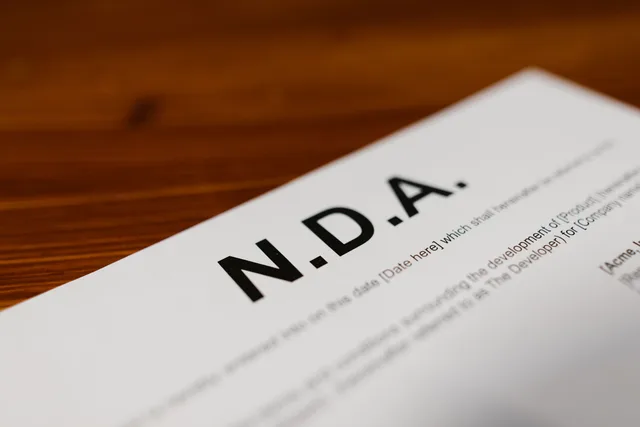 Focused close-up of an NDA document on a wooden desk, highlighting contract details. Compliance benchmarks: the network marketing risk flags that matter