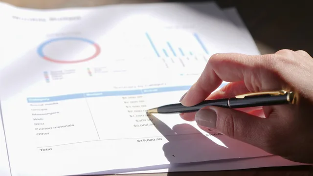 Hand holding pen, analyzing budget with charts and graph paper. The network marketing compliance best practices worth adopting first