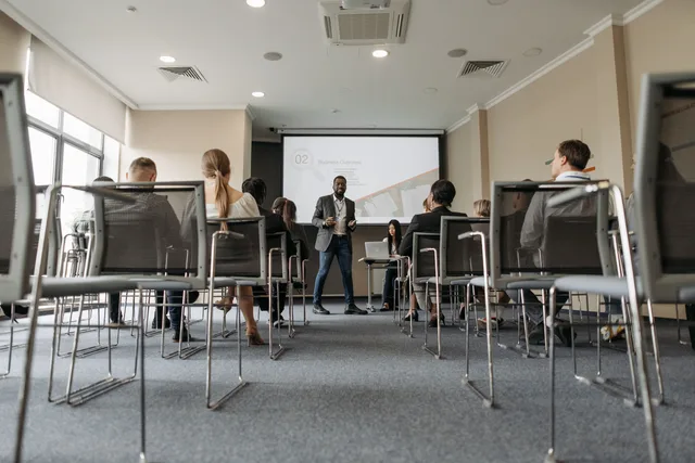 Business seminar with a diverse group, featuring a speaker in a modern conference room. Signals that show where network marketing training is heading